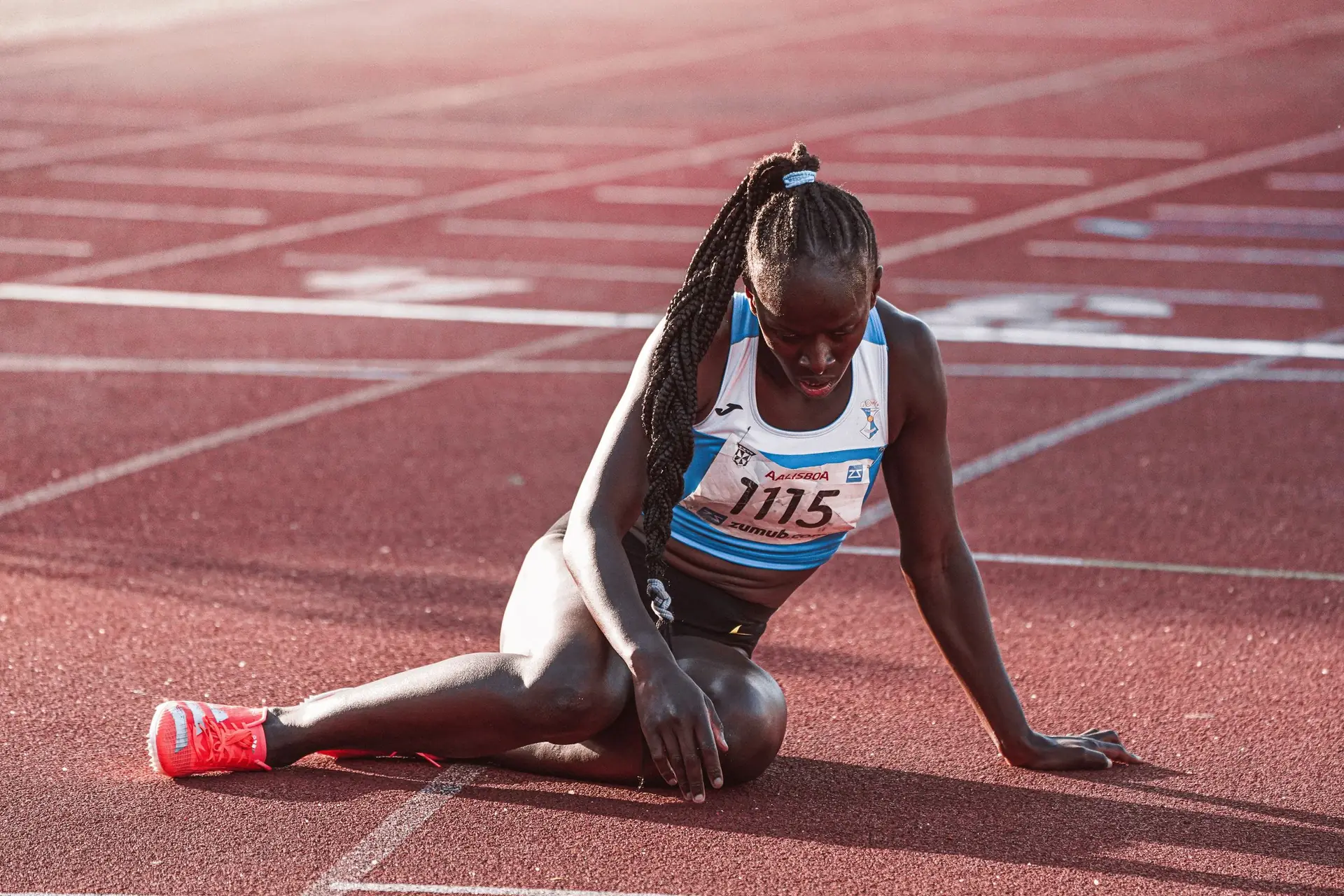 Une athlète assise sur la piste après sa course
