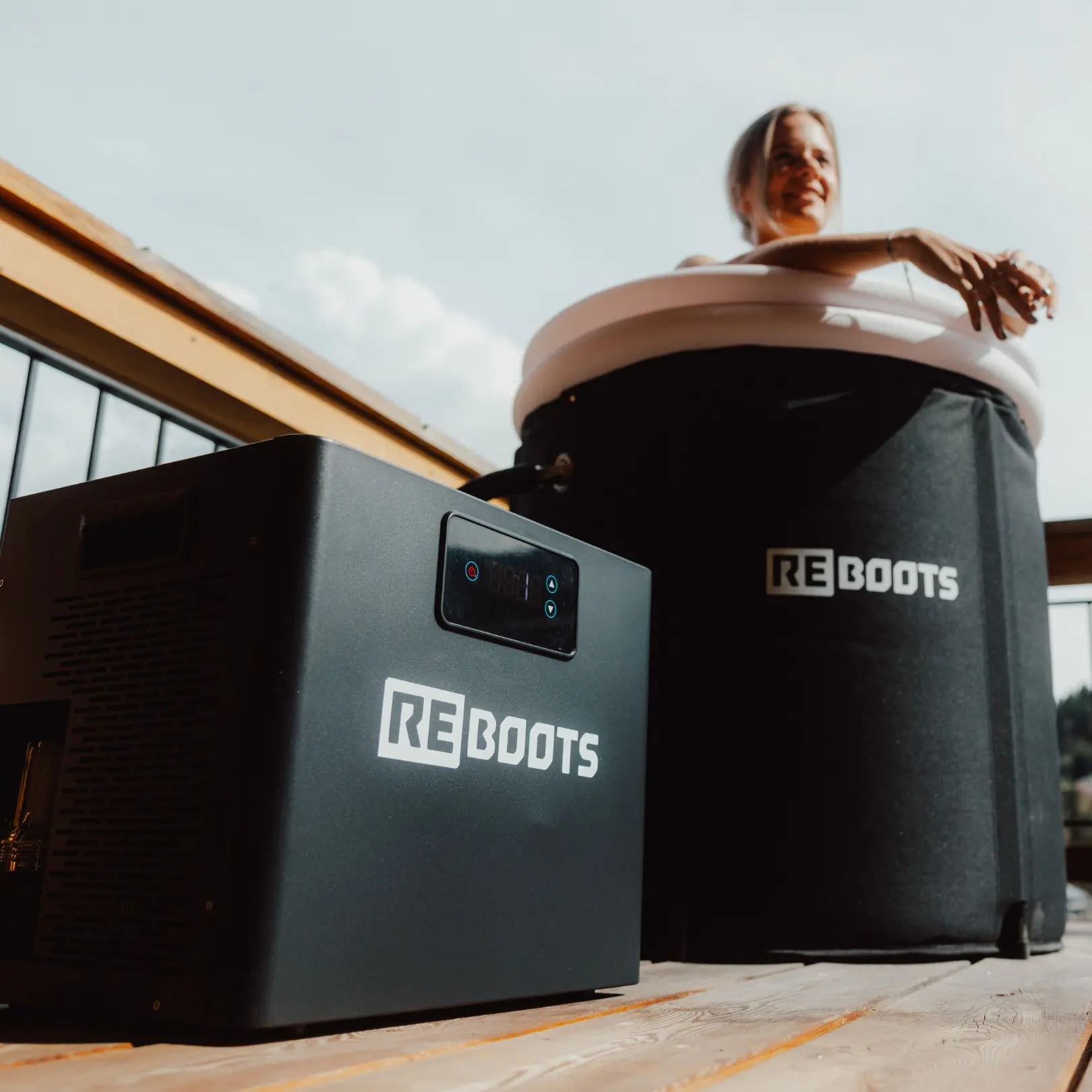 Vue en contre-plongée d'une femme dans l'Ice Tub Pro, groupe froid Reboots au premier plan, ciel dégagé