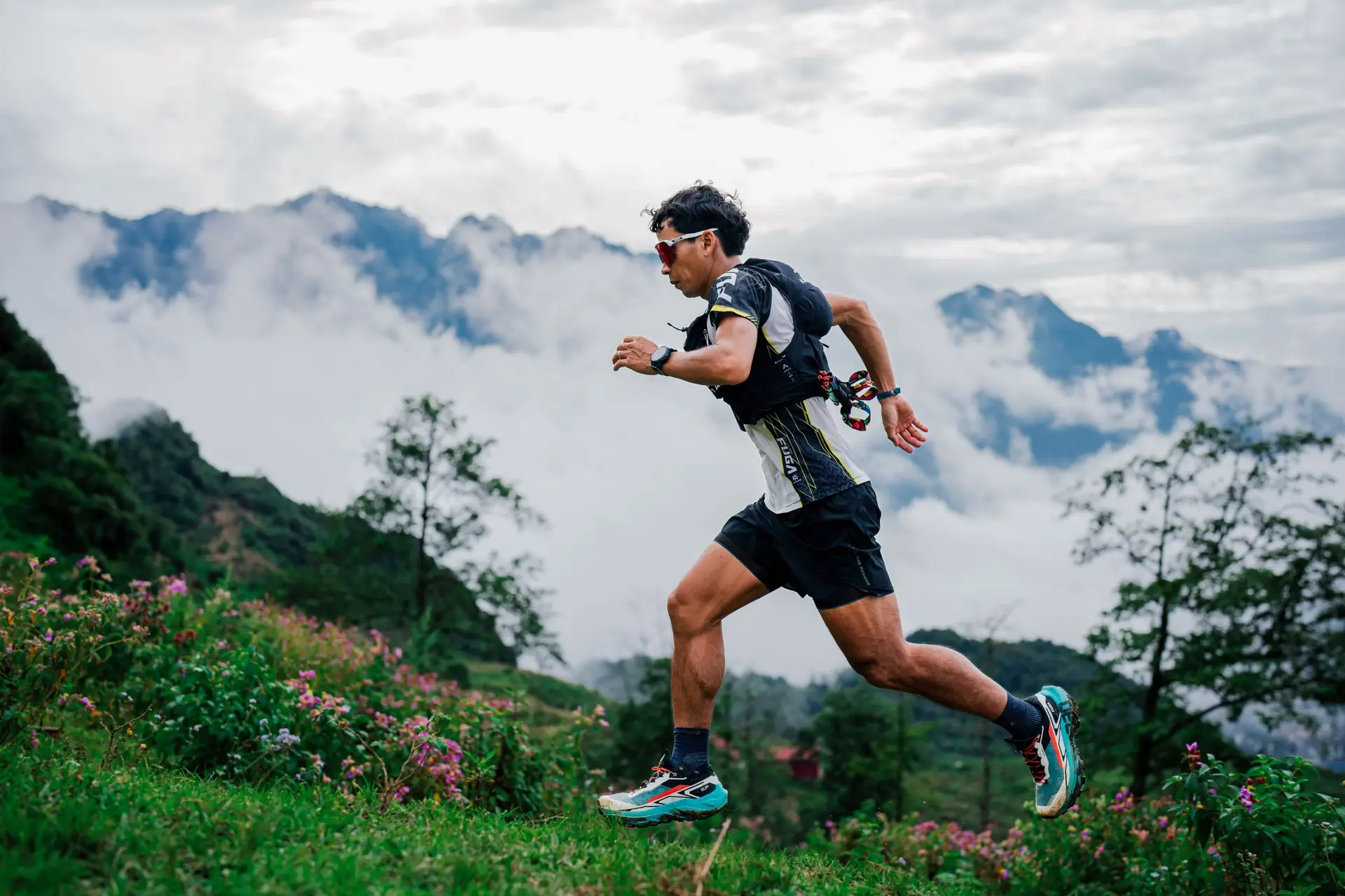 Un coureur de trail sur un sentier de montagne, au-dessus des nuages